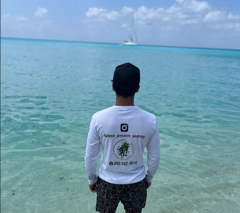 Michael Babun de espaldas, con una camisa de manga larga de Baboon Pressure Washing con el logo y el teléfono